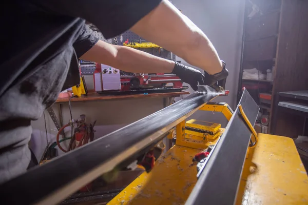 A man repairman in workshop ski service repairing the ski