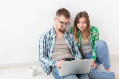 Mutlu genç aile bir dizüstü bilgisayar ve Wi-Fi Internet yardımıyla bir daire için mobilya ve aksesuar online mağaza arayışı içinde Internet Surfs. Online alışveriş ve ev içi konsept.