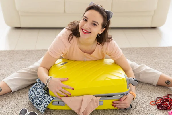 Vacances, voyage et concept de voyage - Jeune femme recueille une valise à la maison dans la chambre à coucher, beaucoup de choses, vacances et valise jaune — Photo