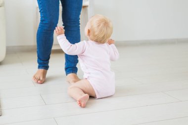Küçük emekleme kız kız bir yaşında parlak ışık oturma odasında katta gülümseyerek ve gülüyor oturuyor. Evde oynayan mutlu bir çocuk. Çocukluk kavramı