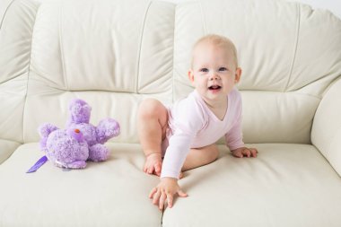 çocukluk, bebeklik ve insan kavramı - evde kanepede oturan mutlu küçük bebek kız