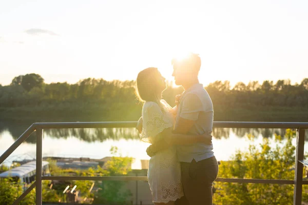 Uomo e donna che si abbracciano al tramonto sulla natura. Coppia in romantico abbraccio — Foto Stock