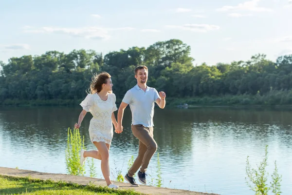 Verão natureza, relacionamento e as pessoas no conceito de amor - casal feliz correndo perto do lago — Fotografia de Stock