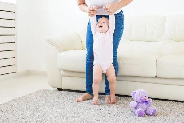 Bébé faire les premiers pas avec les mères aide à la maison — Photo