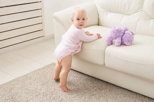 Child, childhood and kids concept - Portrait of charming baby girl near the couch — Stock Photo, Image