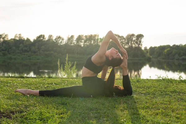 Ung kvinna som gör yoga i parken på en solig dag — Stockfoto