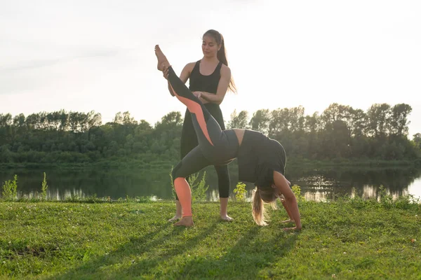 Harmonie und gesundes Lifestylekonzept - junge schlanke Frauen in Sportbekleidung praktizieren Yoga im Freien. — Stockfoto