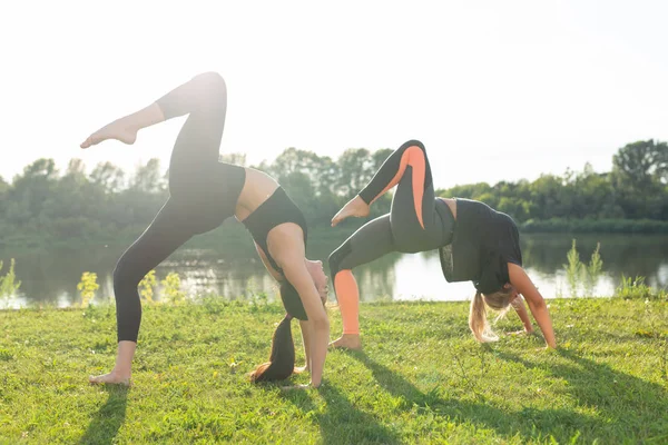 Estilo de vida saudável e conceito de pessoas - Mulheres flexíveis fazendo ioga no parque de verão — Fotografia de Stock