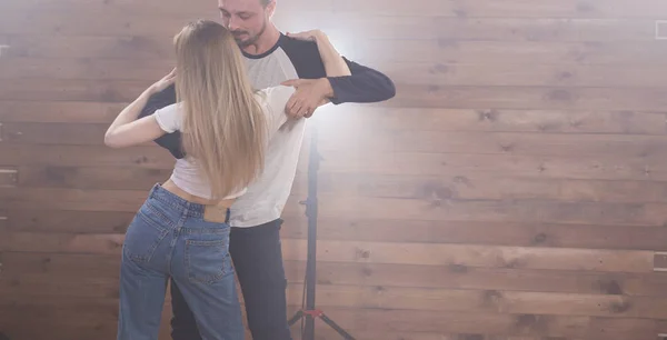 Pareja joven bailando baile latino bachata, merengue, salsa, kizomba. Dos poses expresivas sobre fondo de madera con copyspace — Foto de Stock