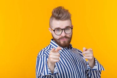 Bir bıyık ve sakal ve gözlük ile komik genç adam sarı bir arka planda size gösterir. Standart olmayan reklam kavramı.