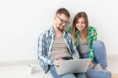 Gülümseyen genç çift yeni ipotek daire mobilya online alımları yapar. Dizüstü bilgisayar ve gadget'lar ile online alışveriş konsepti.