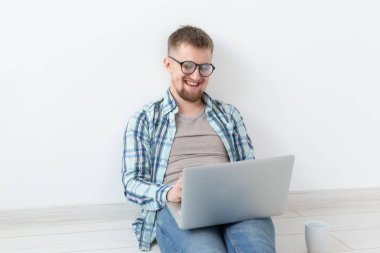 Rahat giysiler ve gözlük Internet Wi-Fi ve Kiralık Konut arayışı içinde bir dizüstü bilgisayar kullanarak sörf olumlu genç adam. Ev ve daire arama konsepti.