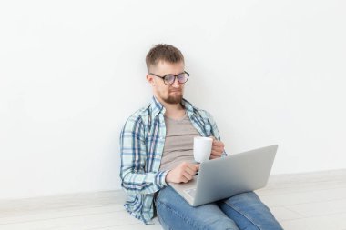 Rahat giysiler ve gözlük Internet Wi-Fi ve Kiralık Konut arayışı içinde bir dizüstü bilgisayar kullanarak sörf olumlu genç adam. Ev ve daire arama konsepti.