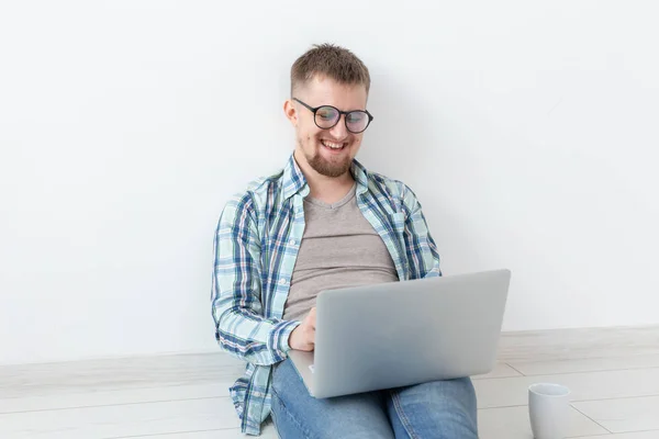 Joven positivo en ropa casual y gafas navegando por Internet a través de Wi-Fi y un portátil en busca de vivienda de alquiler. Concepto de inauguración y búsqueda de apartamentos . — Foto de Stock