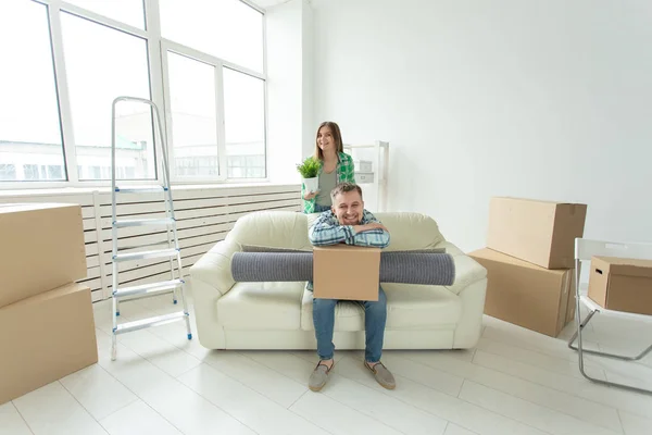 Jovem casal alegre se alegra em se mudar para uma nova casa que estabelece seus pertences na sala de estar. Conceito de aquecimento doméstico e hipotecas para uma família jovem — Fotografia de Stock