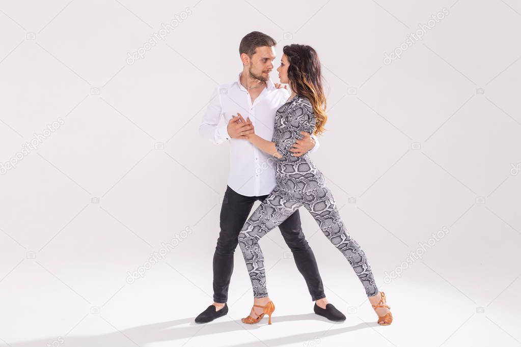Social dance, bachata, kizomba, zouk, tango concept - Man hugs woman while dancing over white background with copy space