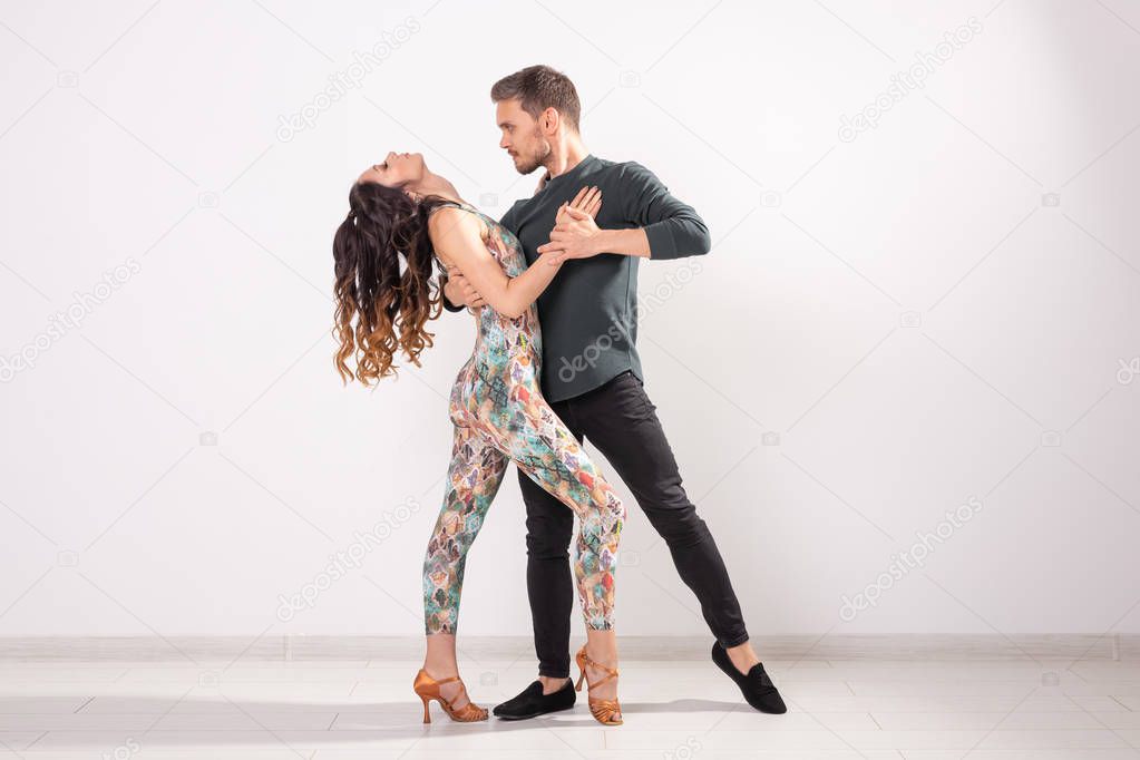 Social dance, bachata, kizomba, zouk, tango concept - Man hugs woman while dancing over white background with copy space