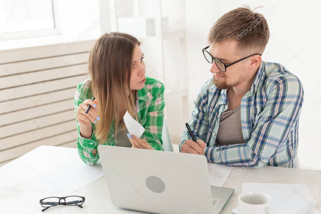 Dissatisfied young husband and wife recount utility bills for payment of an apartment and write the results in a notebook and laptop in their home accounting.