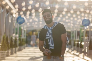 Sıcak güneşli bir yaz gününde parkta yürürken bir saman ile meyve suyu bir bardak ile olumlu neşeli bir genç Arap adam Portresi. Çalışma sonrası dinlenme kavramı ve hafta sonları çalışma.