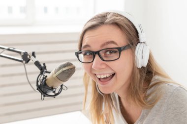 Radyo, bloglama, podcasting kavramı - radyoda dj olarak çalışan genç kadının yakın çekim.