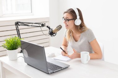 Radyo host kavramı - Kadın stüdyoda beyaz arka plan üzerinde mikrofon önünde oturan radyo host olarak çalışan