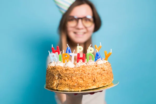 파란색 배경에 서 그녀의 손에 생일 케이크를 들고 축하 종이 모자에 매력적인 메리 미친 어린 소녀 학생. 광고 공간. — 스톡 사진