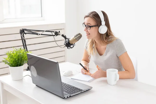 Concetto di conduttore radiofonico - Donna che lavora come conduttrice radiofonica seduta davanti al microfono su sfondo bianco in studio — Foto Stock