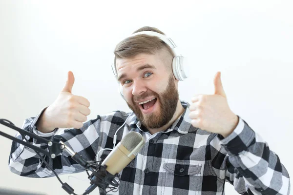 Podcasting, music and radio concept - Happy man with microphone and big headphone — Stock Photo, Image