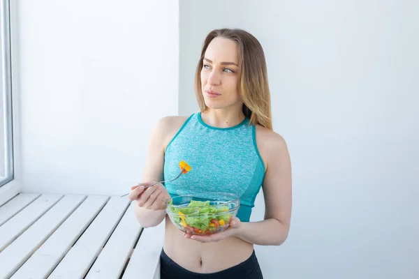 Stile di vita sano, fitness e dieta concetto - insalata dietetica e donna in abbigliamento sportivo — Foto Stock