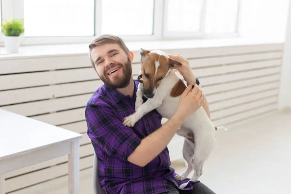 Menschen, Haustiere und Heimkonzept - Junger Mann spielt mit Jack Russell Terrier Welpe — Stockfoto