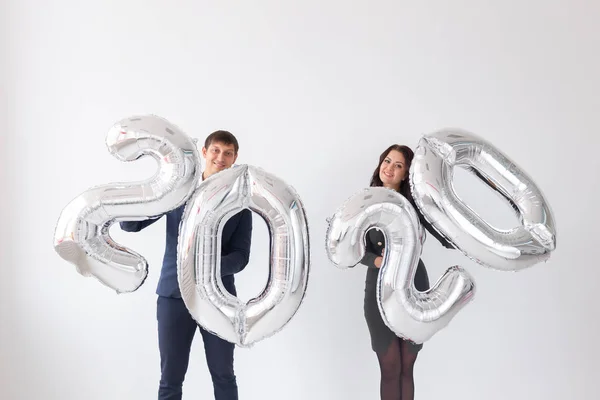 Nytt år, firande och helgdagar Concept-kärlekspar ha kul med skylt 2020 gjord av silver ballonger för nyår på vit bakgrund — Stockfoto