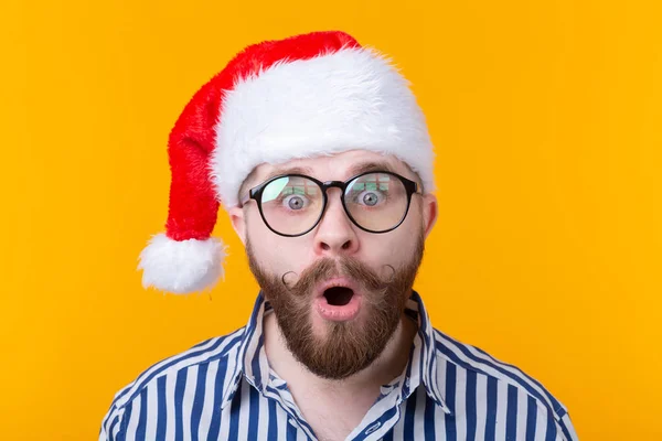 Sorprendido joven Santa Claus mirando a la cámara sobre un fondo amarillo. El concepto de felicitaciones por el Año Nuevo y la Navidad. Espacio publicitario . —  Fotos de Stock