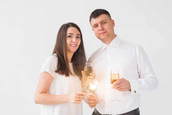 Νέο έτος, διακοπές, ημερομηνία και την ημέρα του Αγίου Βαλεντίνου έννοια-αγαπητό ζευγάρι κρατώντας τα βεγγαλικά φως και τα ποτήρια της σαμπάνιας σε λευκό φόντο — Φωτογραφία Αρχείου