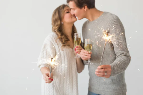新年、休日、日付、バレンタインデーのコンセプト - 白い背景の上にシャンパンのスパークラーライトとグラスを保持する愛するカップル、クローズアップ — ストック写真