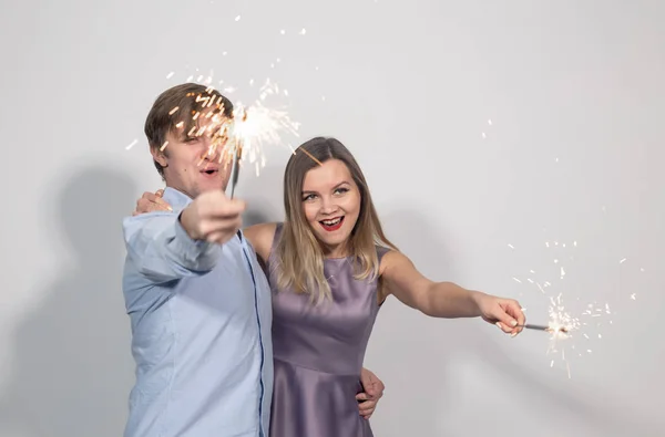Festa, ano novo, diversão de Natal e conceito de feriados - jovem casal feliz com brilhos no fundo branco — Fotografia de Stock