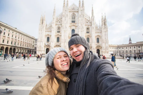 Travel, Italy and funny couple concept - Happy tourists taking a self portrait in front of Duomo cathedral, Milan