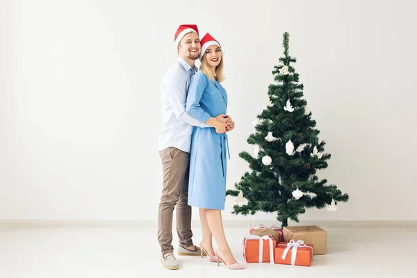 Vacaciones de invierno y concepto familiar - Feliz pareja joven cerca del árbol de Navidad en casa — Foto de Stock