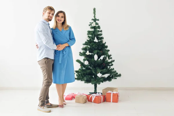 Vacaciones de invierno y concepto familiar - Feliz pareja joven cerca del árbol de Navidad en casa — Foto de Stock