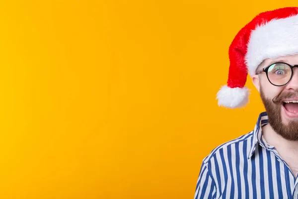 Vrolijke gekke schattige jonge hipster man in rode Santa Claus hoed poseren over gele achtergrond. Het concept van Kerstmis en het nieuwe jaar. Advertentieruimte. — Stockfoto