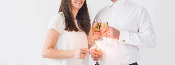 Ano Novo, feriados, data e dia dos namorados conceito - casal amoroso segurando faíscas luz e copos de champanhe close-up sobre fundo branco — Fotografia de Stock