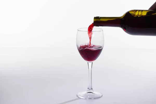 Pouring red wine into the glass on white background with copy space Stock Image