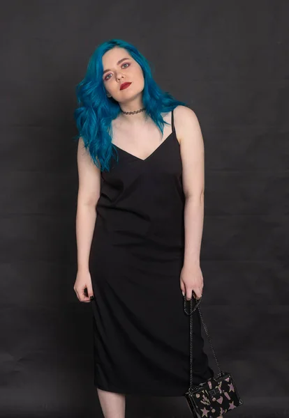 Ludzie i koncepcja mody-kobieta ubrana w czarną sukienkę i niebieskie włosy stwarzające na czarnym tle — Zdjęcie stockowe