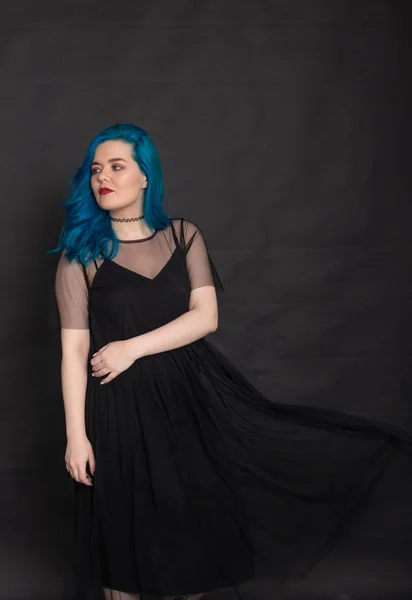人物和时尚概念 - 身着黑色连衣裙和蓝色头发的女人在黑色背景上摆姿势 — 图库照片