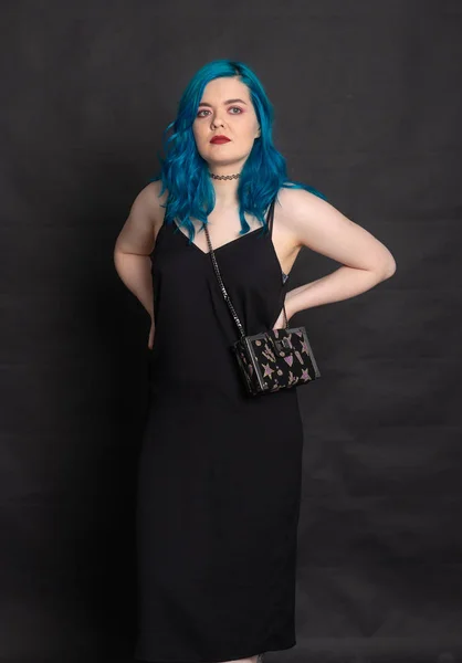Ludzie i koncepcja mody-kobieta ubrana w czarną sukienkę i niebieskie włosy stwarzające na czarnym tle — Zdjęcie stockowe
