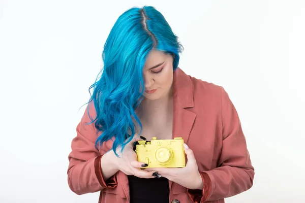 Люди, хобби и интересы - девушка с синими волосами держит желтую ретро-камеру на белом фоне — стоковое фото