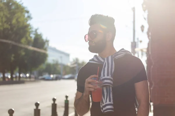 口ひげとあごひげを持つかわいいスタイリッシュなアラブの若い男性ヒップスターとストローでジュースを飲んでメガネを着用。夏休みのコンセプト. — ストック写真