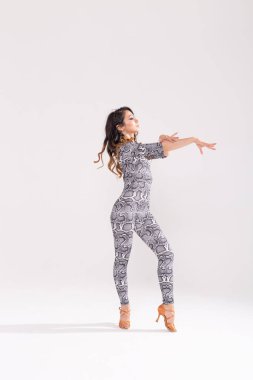 Latin dansı, striptiz dansı, çağdaş ve bachata bayan konsepti - doğaçlama dans eden ve uzun saçlarını beyaz arka planda gezdiren kadın