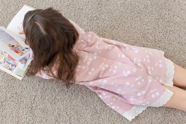 Mädchen liegt auf dem Boden und liest ein Buch. — Stockfoto