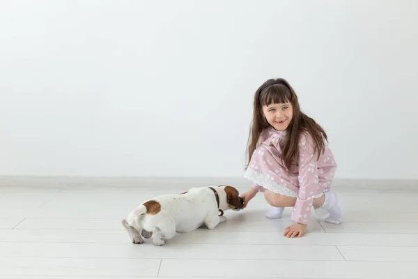 Liten barnflicka i en rosa klänning leker med sin hund Jack Russell Terrier — Stockfoto