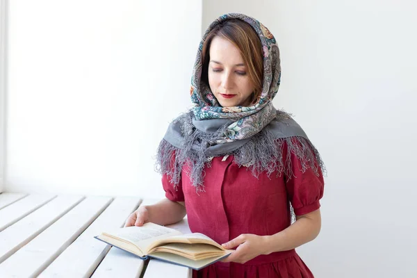 Retrato de close-up de uma jovem mulher de sonho bonito com um livro na mão olhando pela janela e pensando em algo. Concept amantes de clássicos e literatura . — Fotografia de Stock